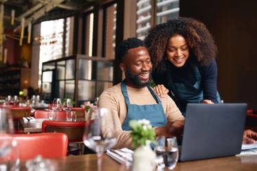 Man And Woman Looking At Laptop In Restaurant